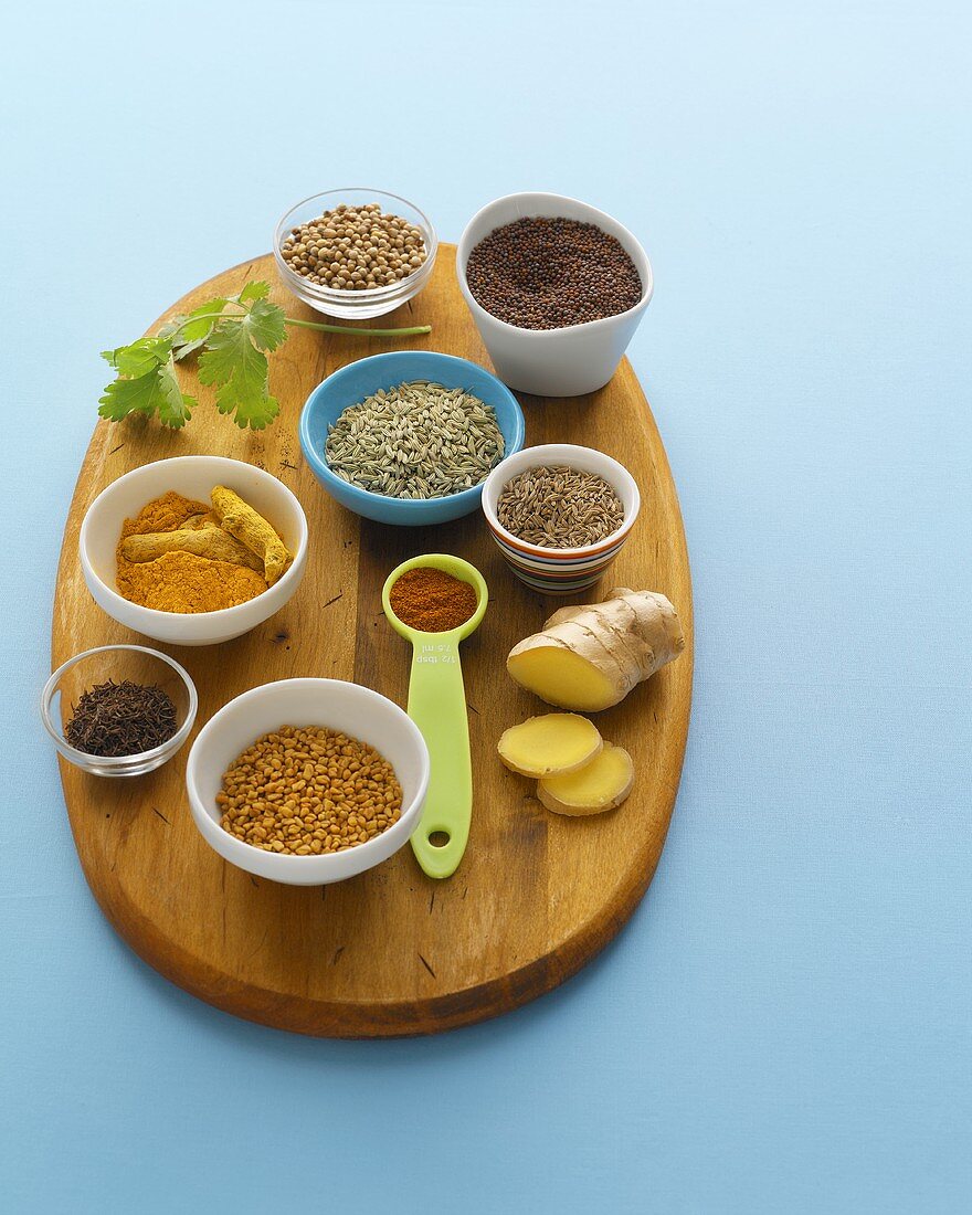 Various spices in small dishes on a wooden board