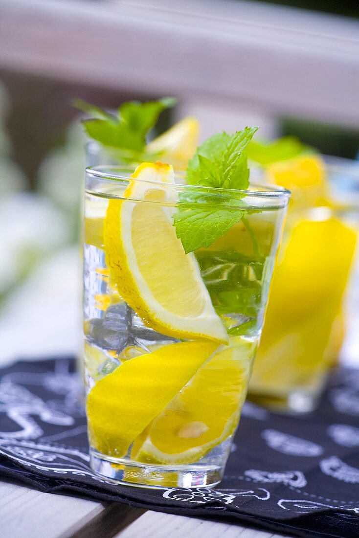Mineralwasser mit Zitronenschnitzen und Minzblättern