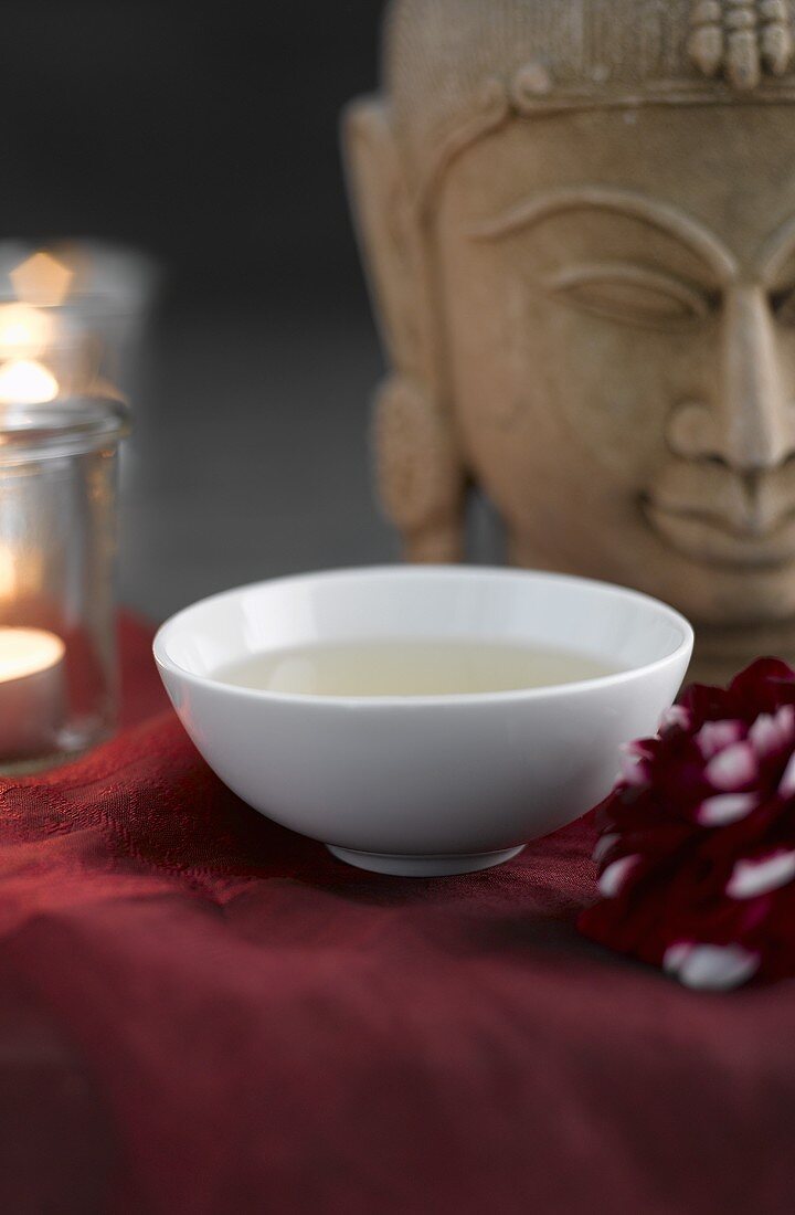 Green tea in tea bowl, Buddha head in background