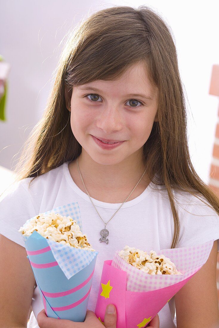 Girl holding two cones of popcorn