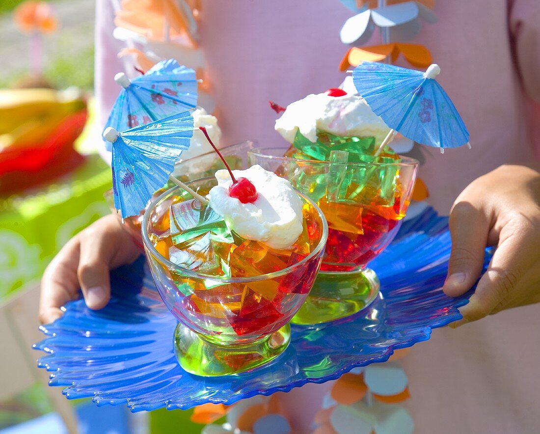 Coloured jelly cubes with cream, cocktail cherries, umbrellas