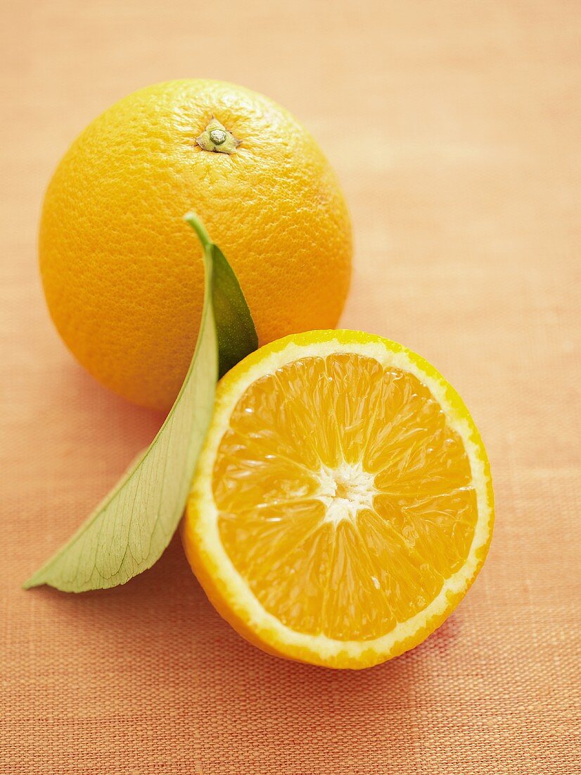 Orangenhälfte und ganze Orange mit Blatt