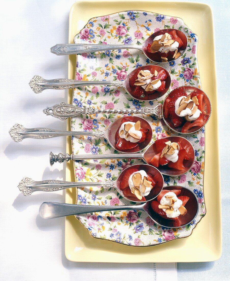 Appetisers on spoons: strawberries with cream and almonds