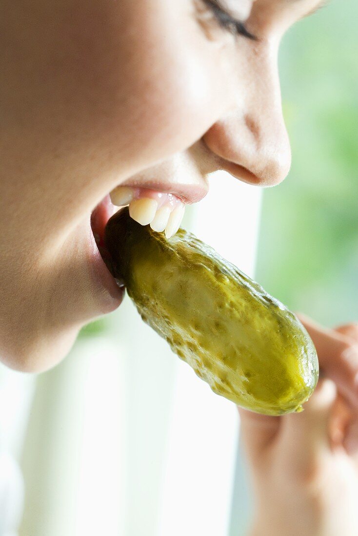 Young woman eating a pickled gherkin