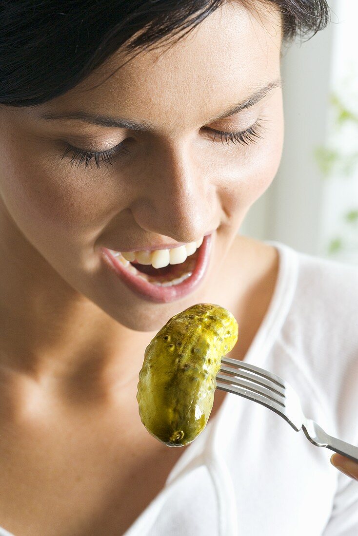 Young woman eating a pickled gherkin