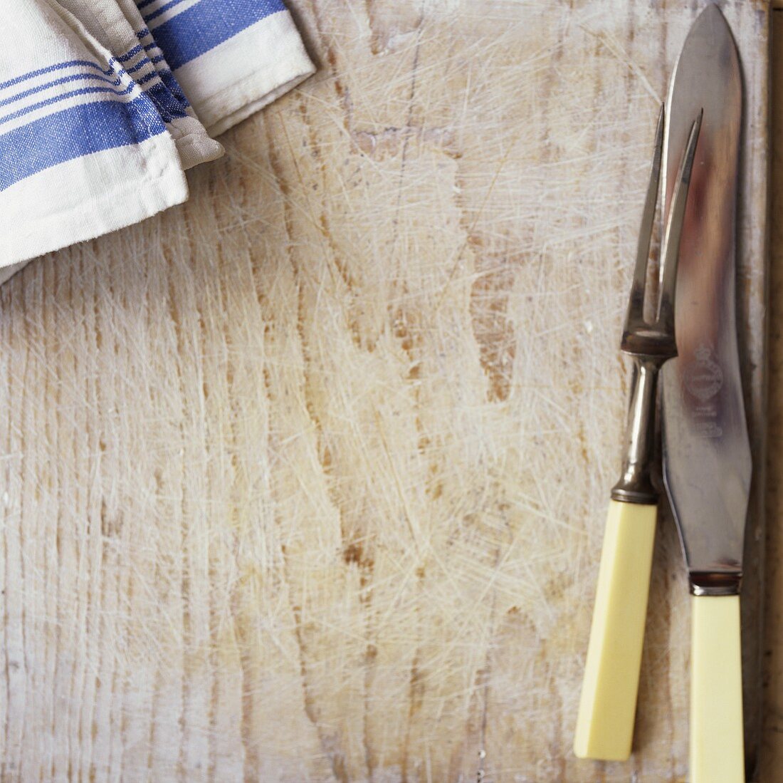 Wooden board, carving fork, knife and tea towel