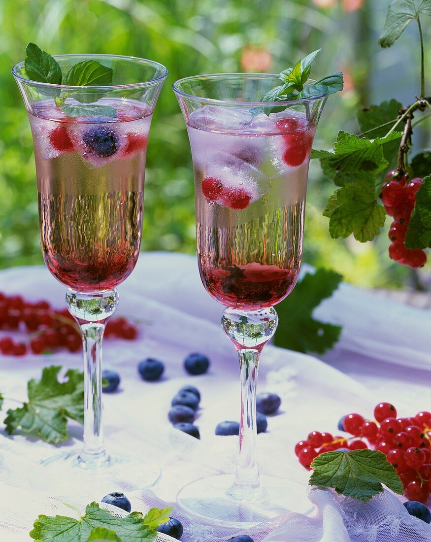 Drinks with redcurrant syrup and berry ice cubes