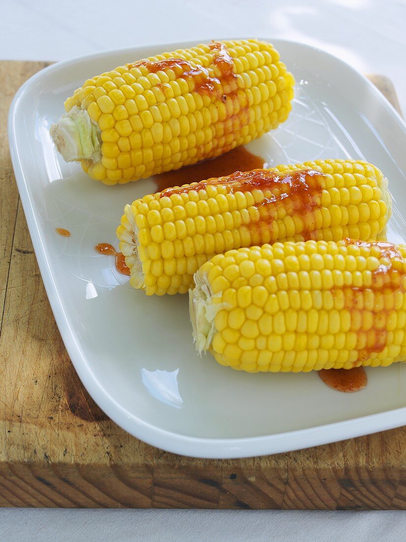 Cooked corn on the cob with chilli sauce