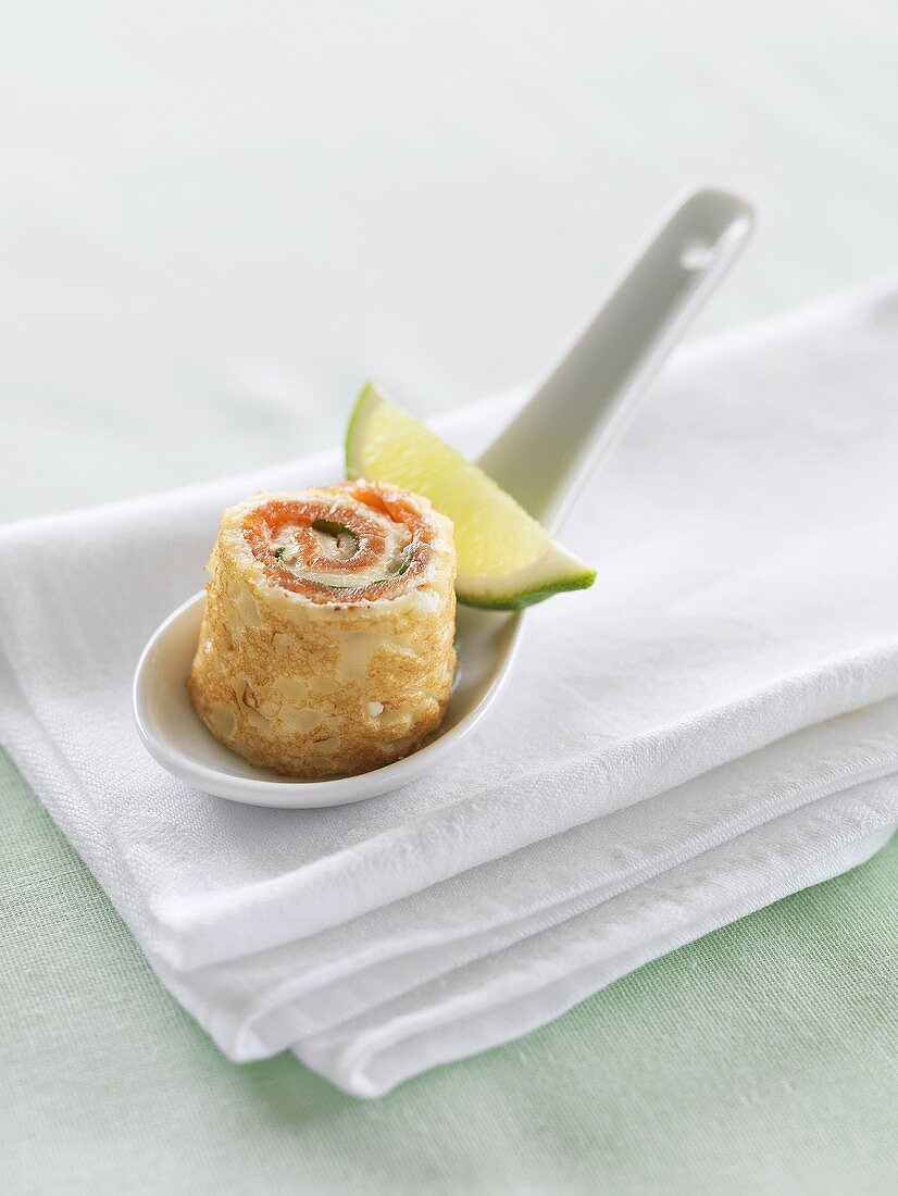 Pancake roll filled with smoked salmon on porcelain spoon