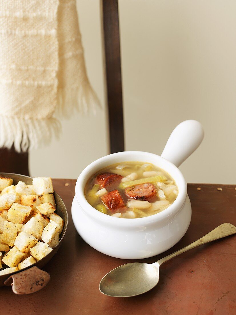 Suppe mit weissen Bohnen, Lauch und Wurst, daneben Croûtons