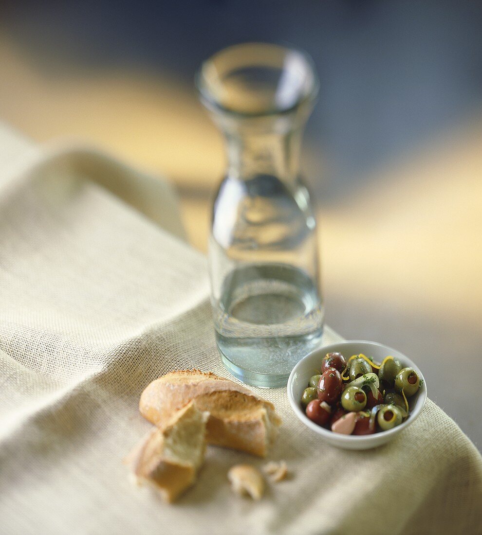 Pickled olives, pieces of baguette and a carafe of water