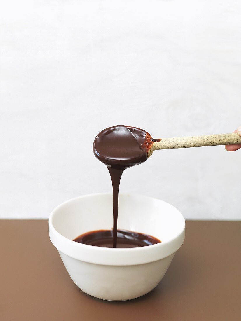 Home-made chocolate sauce running from a wooden spoon