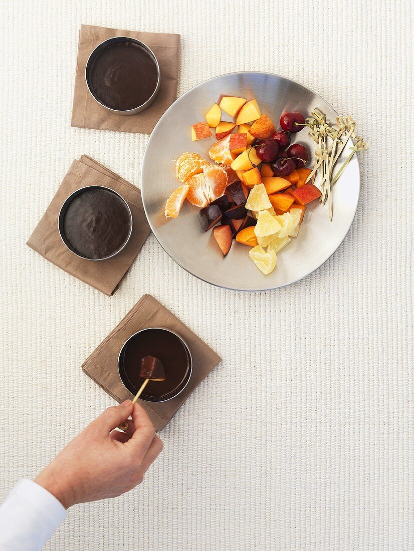 Hand dipping fruit in chocolate sauce