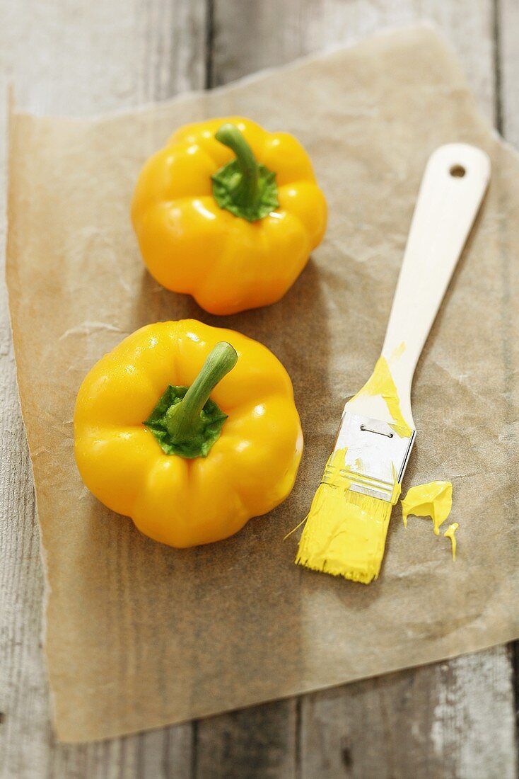 Two yellow peppers with brush and paint