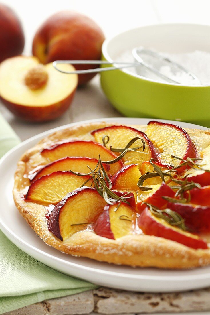 Sweet pizza topped with peach slices and rosemary