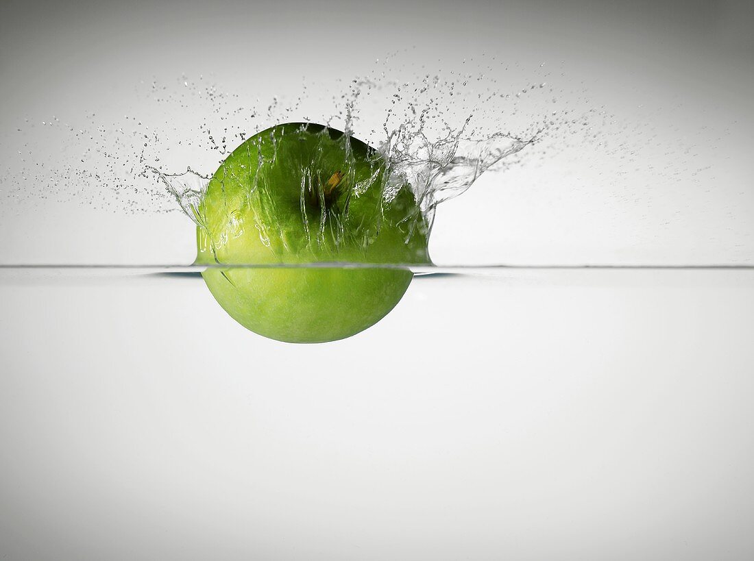 Green apple falling into water