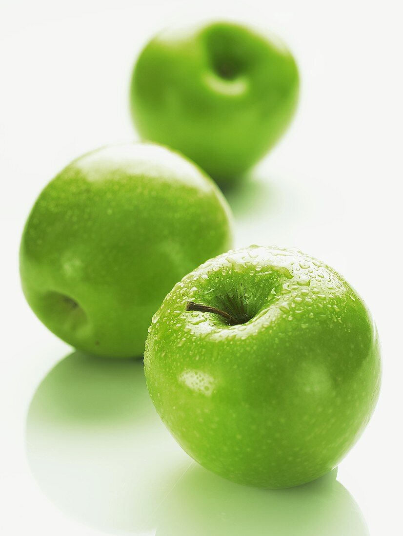 Three green apples (Granny Smith) with drops of water