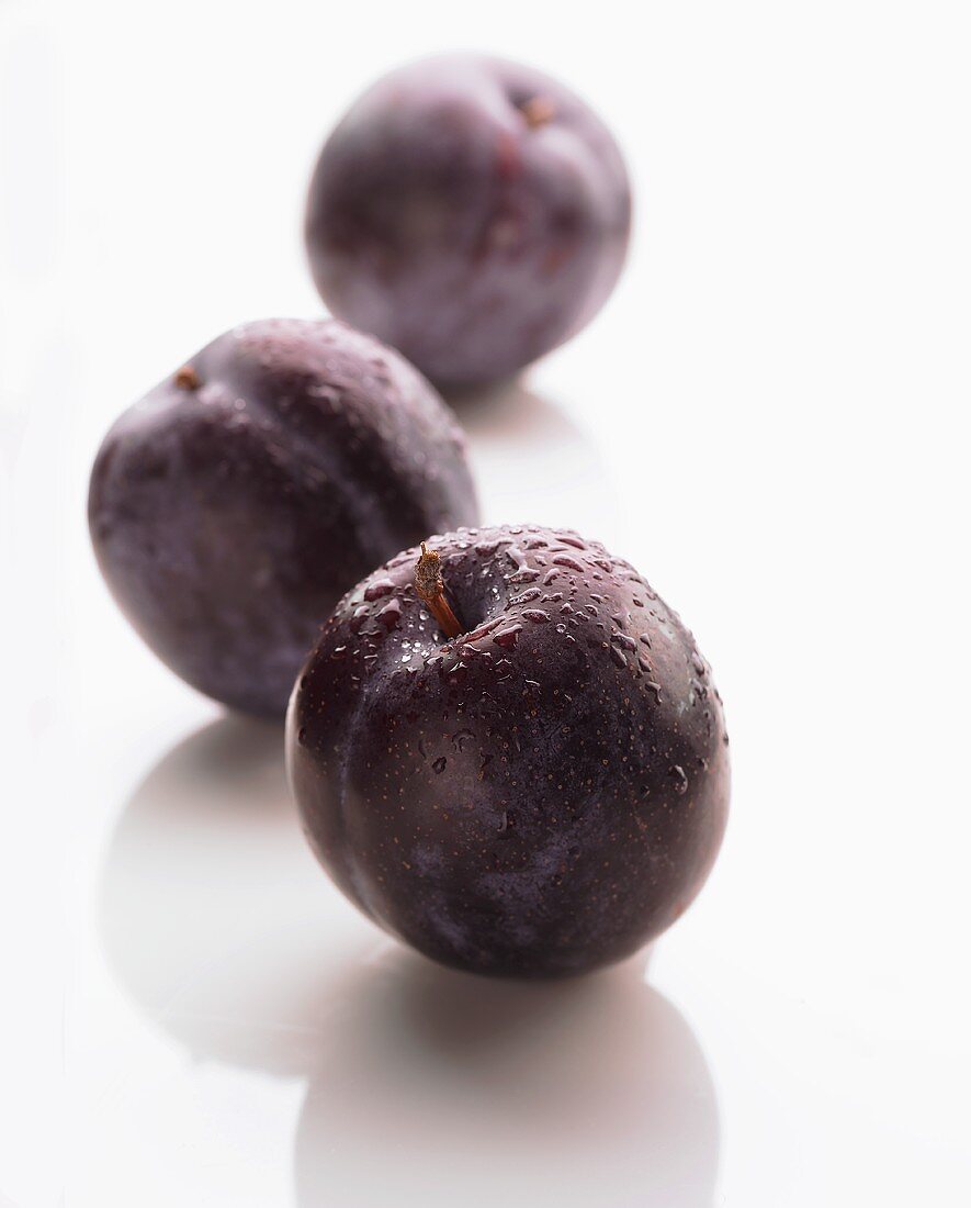 Three plums with drops of water