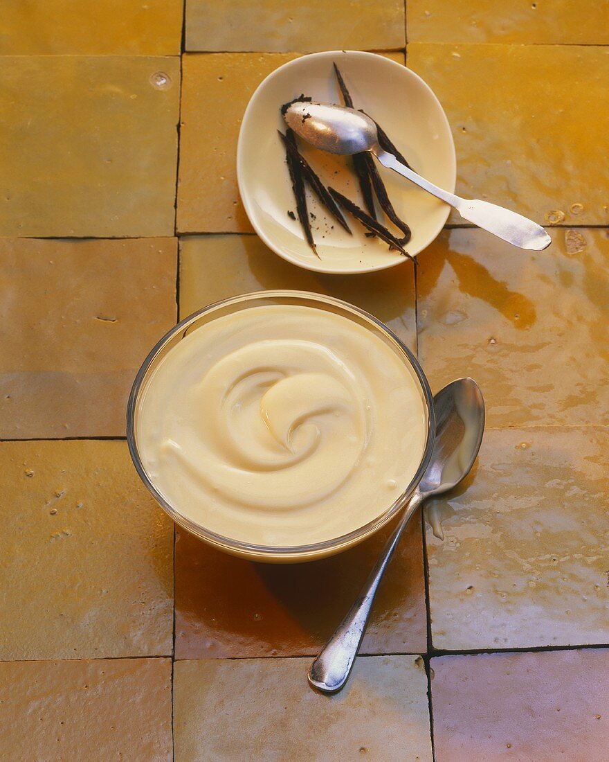 Vanilla cream with vanilla pods on tiled surface