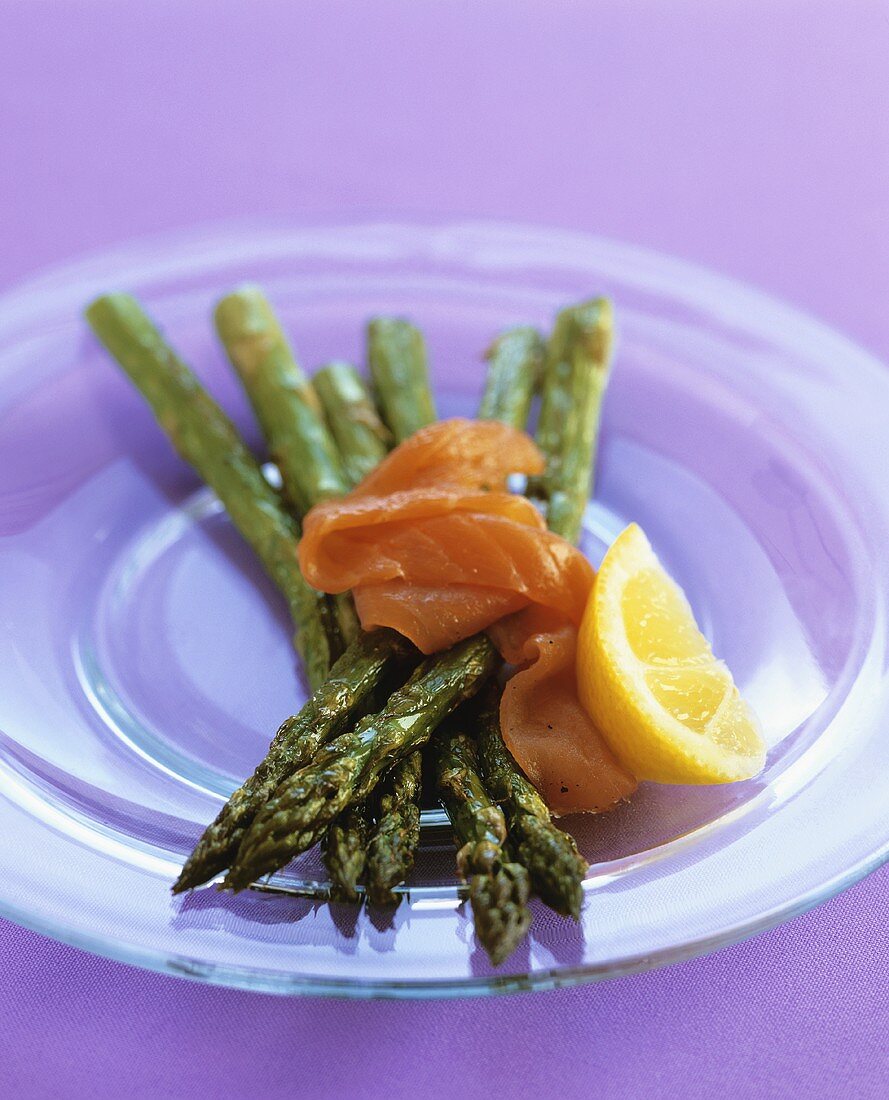 Green asparagus with smoked salmon on glass plate