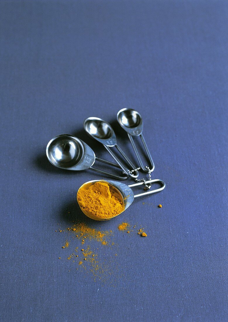 Measuring spoons, one full of curry powder