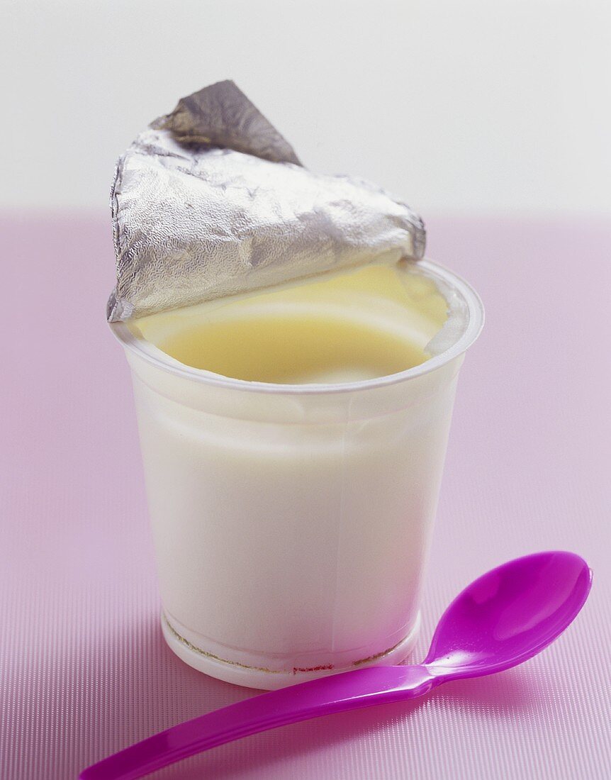 Ein Becher Naturjoghurt mit Plastiklöffel