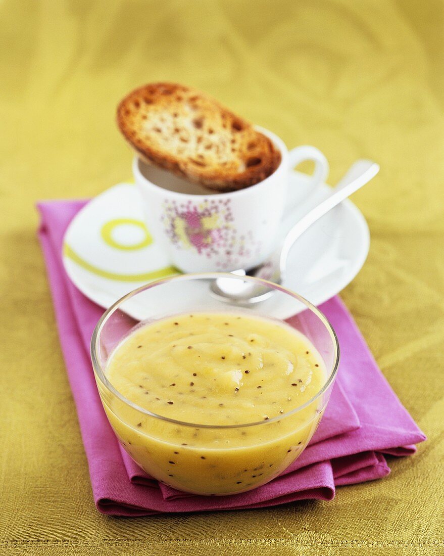 Apfel-Kiwi-Mus und eine Scheibe Röstbrot auf Kaffeetasse