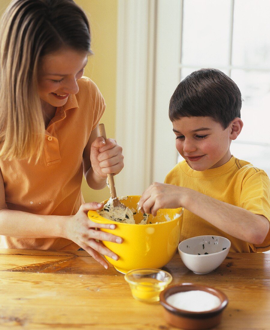 Girl and boy mixing ricotta with herbs