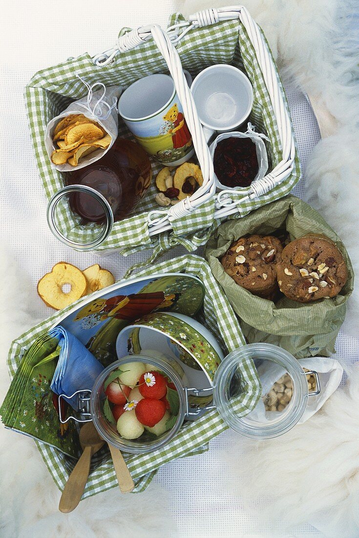Fruit salad, dried fruit and biscuits in picnic baskets