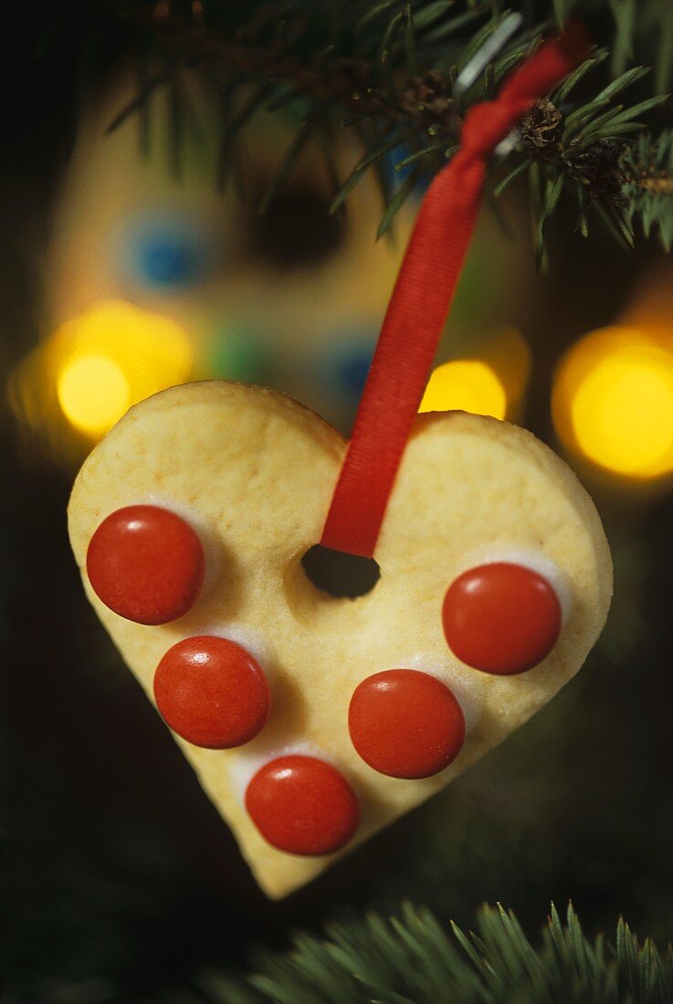 Heart-shaped biscuit with red chocolate beans to hang on the tree