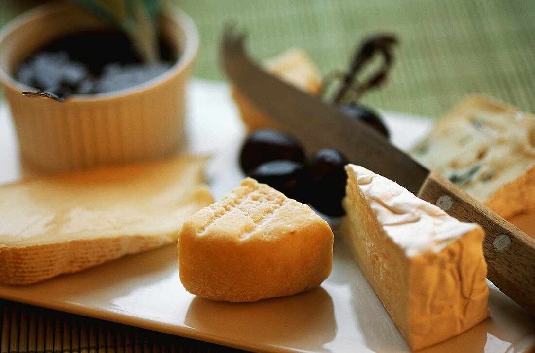 Various types of soft cheese on a cheese board with a cheese knife