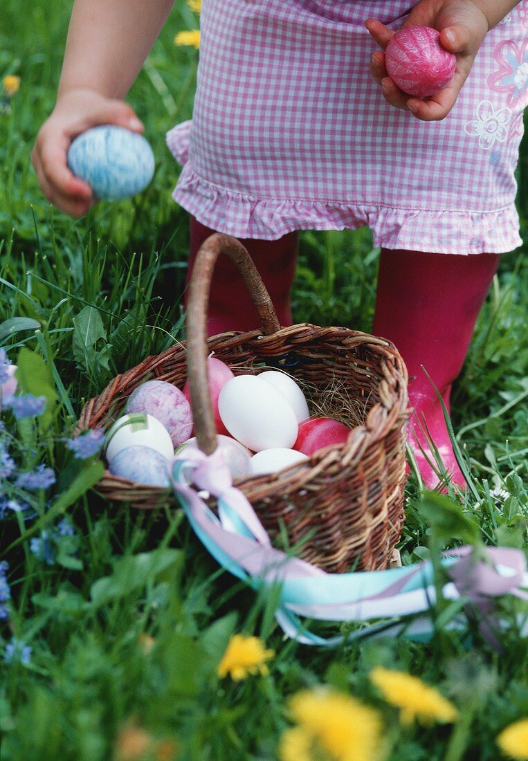 A girl standing behind a basket of Easter eggs