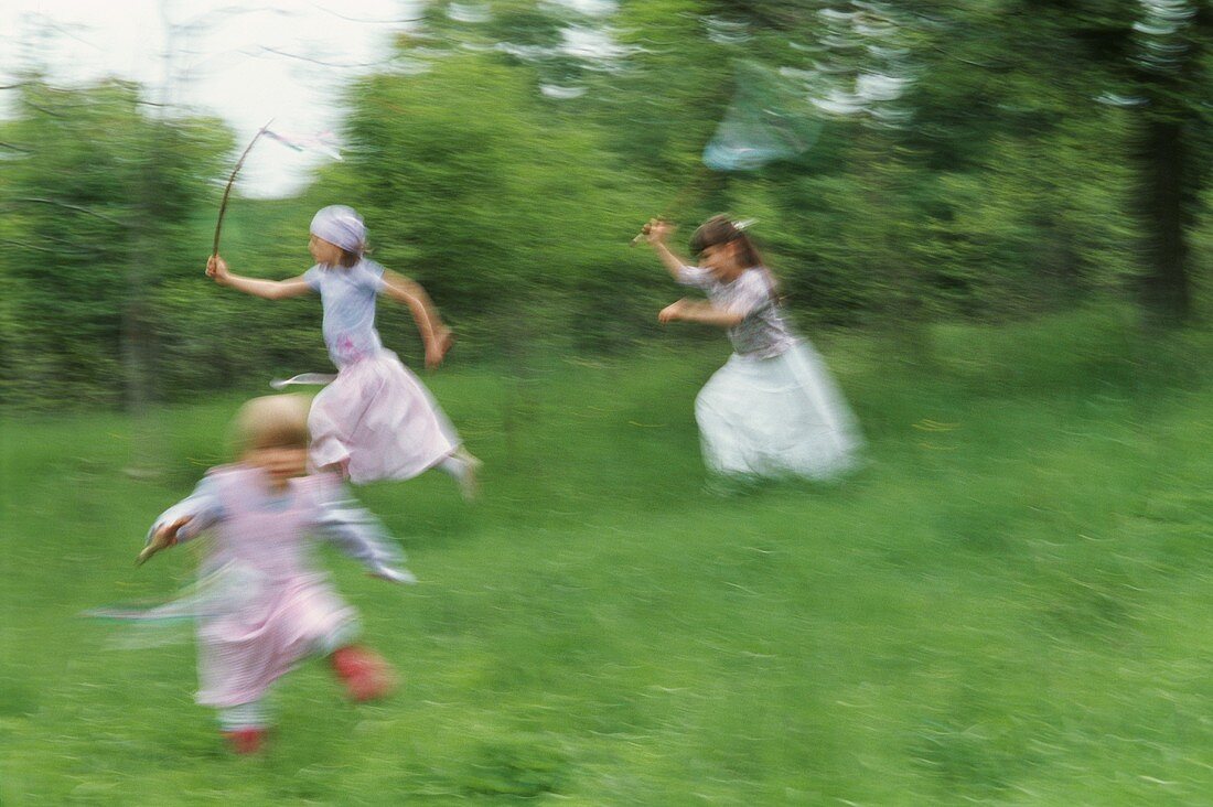 Three girls skipping through the grass