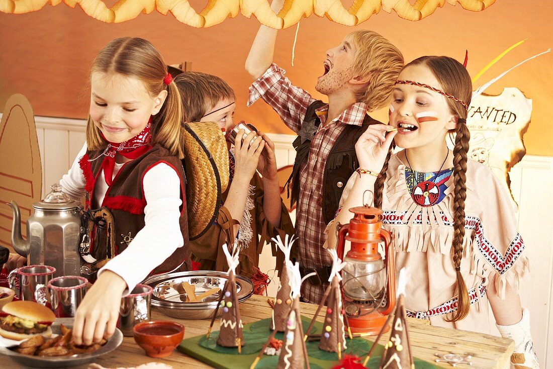 Four children dressed as cowboys and Indians at a party buffet