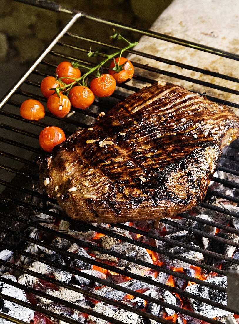 Grilled beef steak with cherry tomatoes on a barbeque