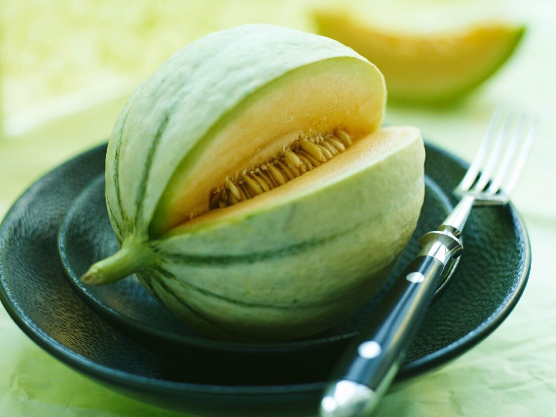 A sliced Cavaillon melon, on a plate with a fork