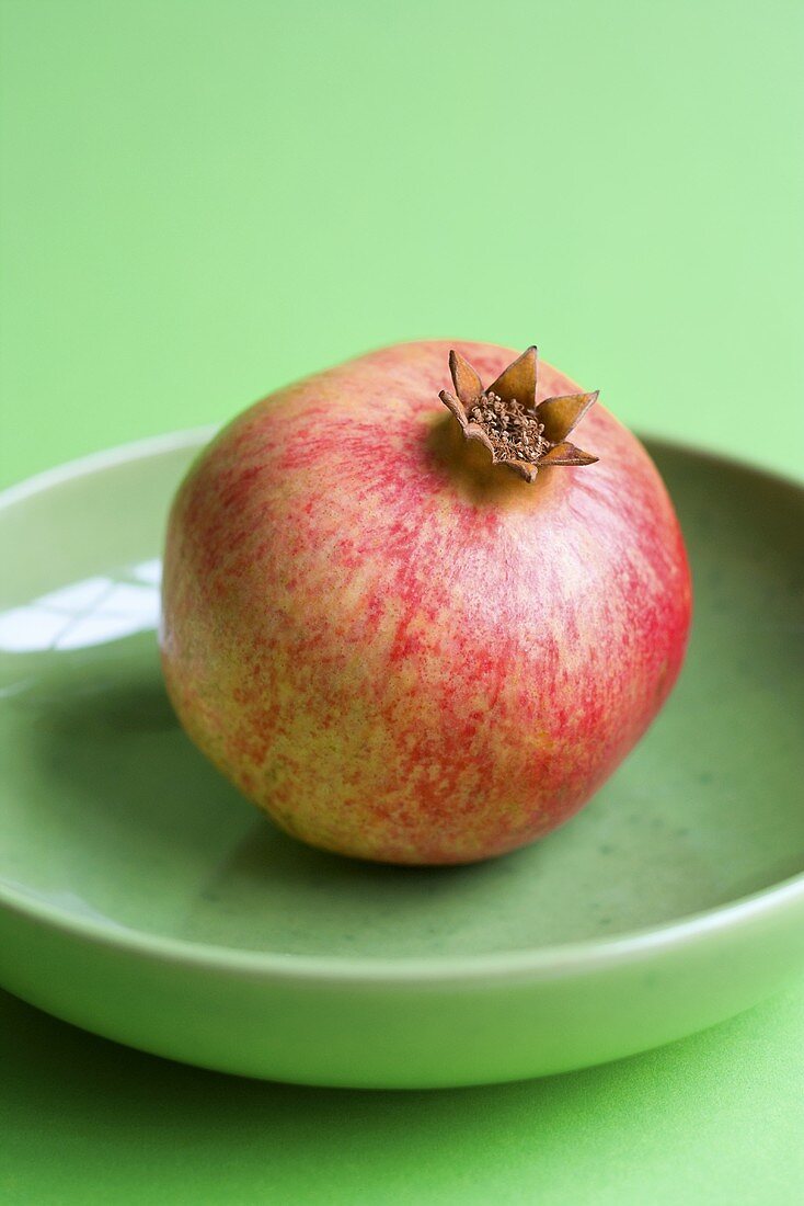 Ein Granatapfel auf grünem Teller