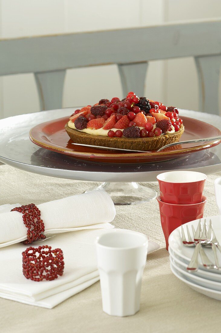 A berry tart on a table with napkins, plates and beakers