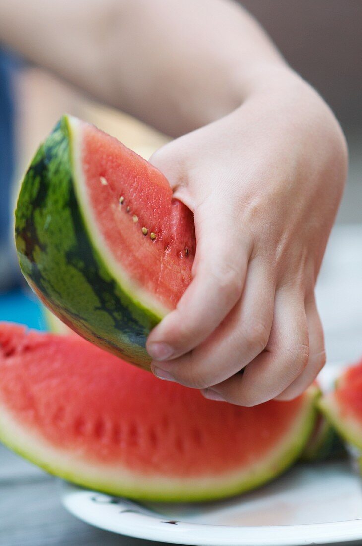 Hand greift Wassermelonenstück