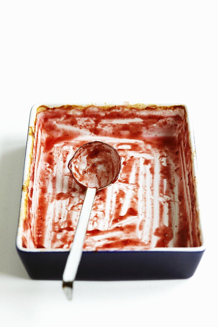 An oven-proof dish and a ladle with leftover jam