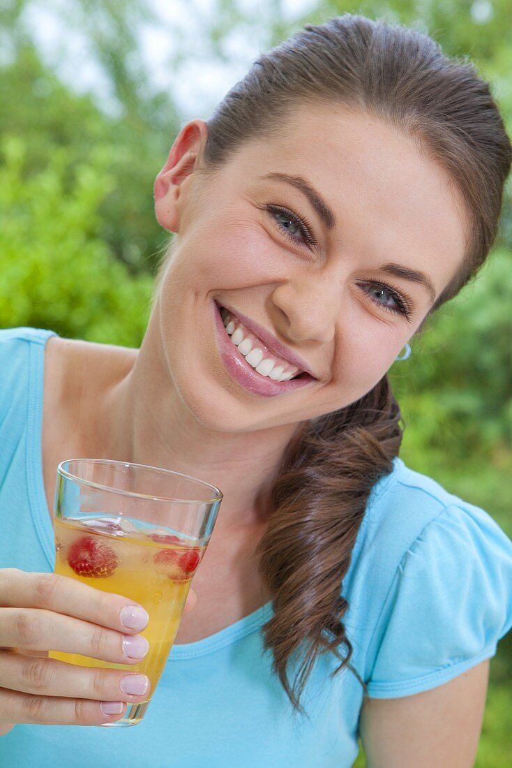 Mädchen hält Glas mit Orangenlimonade