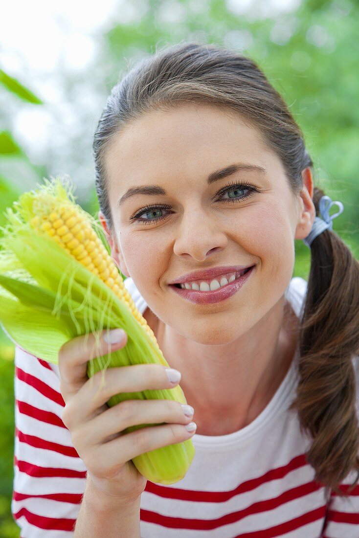 A girl holding a corn cob