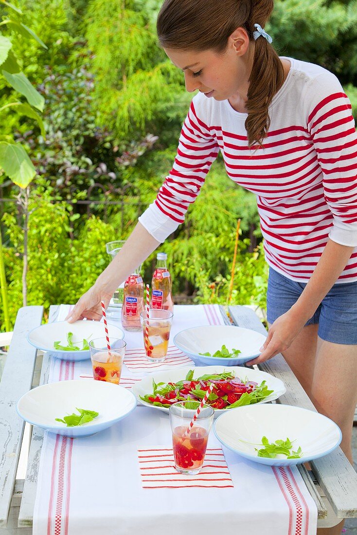 Mädchen serviert Tomaten-Rucola-Salat im Freien
