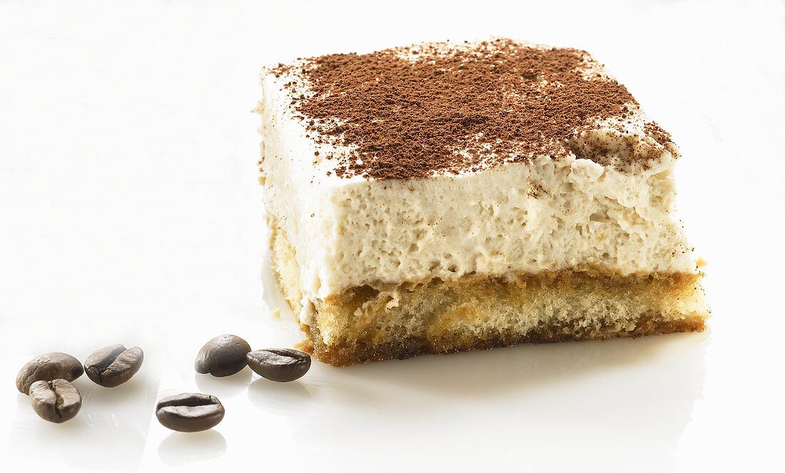 A piece of tiramisu and coffee beans