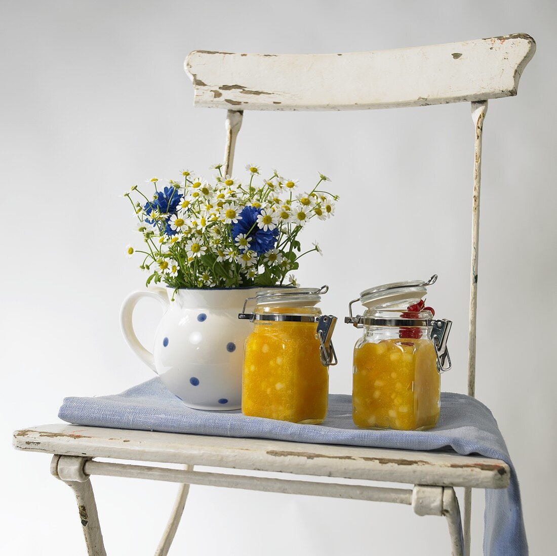 Pineapple jam and a bunch of meadow flowers on a garden chair