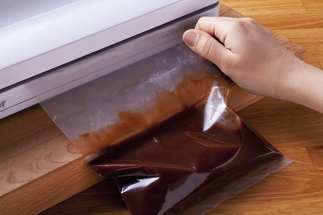 A bag of sauce being closed in a bag sealer