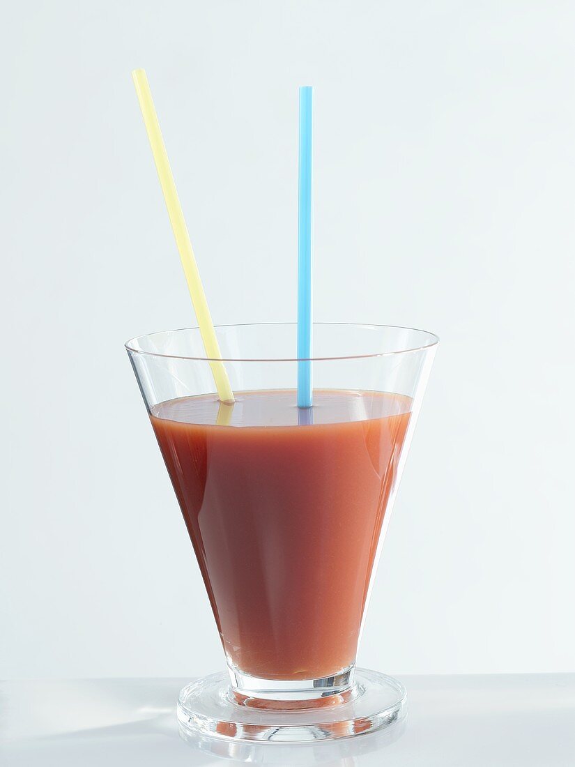 A glass of tomato juice with two straws