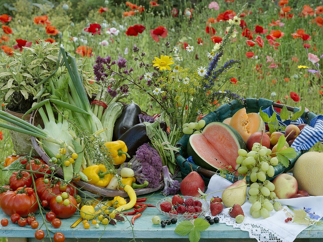 An arrangement of vegetables and fruit with a poppy field in the background