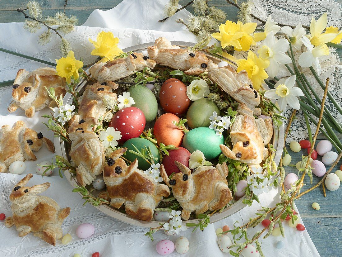 An arrangement of coloured eggs, sugar eggs, Easter bunny bread and narcicus