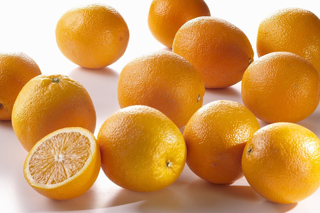 Mehrere ganze Orangen und eine Orangenhälfte